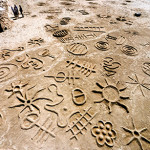 Recreating rock engravings on the beach as aprt of a land art project, South Africa